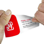 A close-up of two hands peeling back a white business card from a red backing strip. The card has placeholder text and a red-and-white logo, shown against a plain white background.